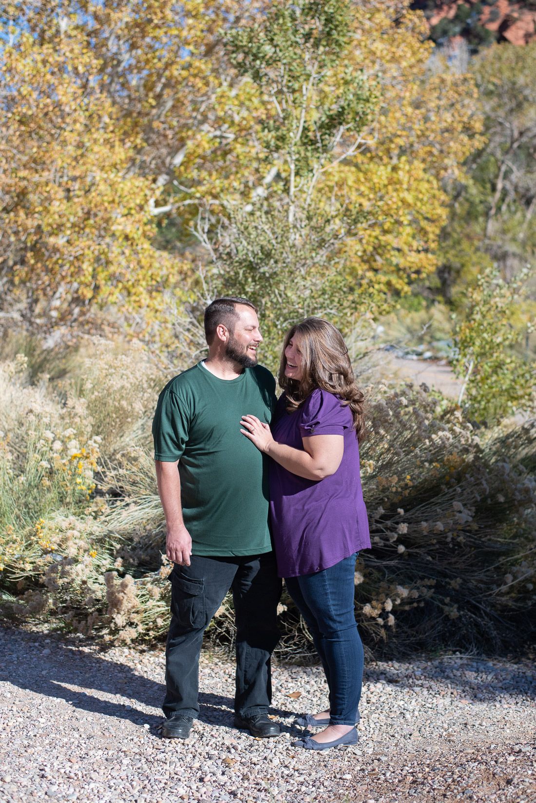Mom and dad standing in front of yellow fall leaves and laughing-Bethany Allen Photography