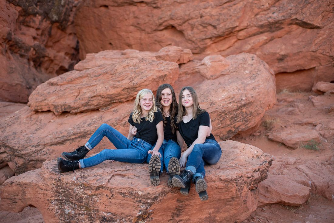 3 teenage sisters sitting on red rocks in St. George