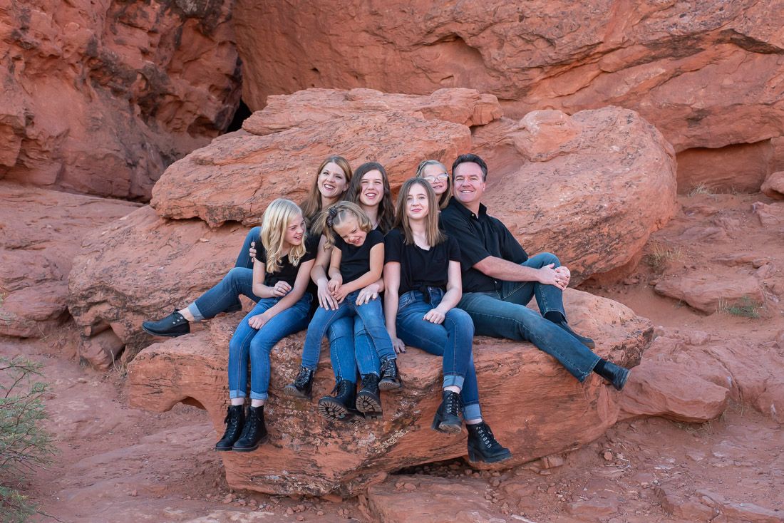 Family sitting on a large rock together and smiling