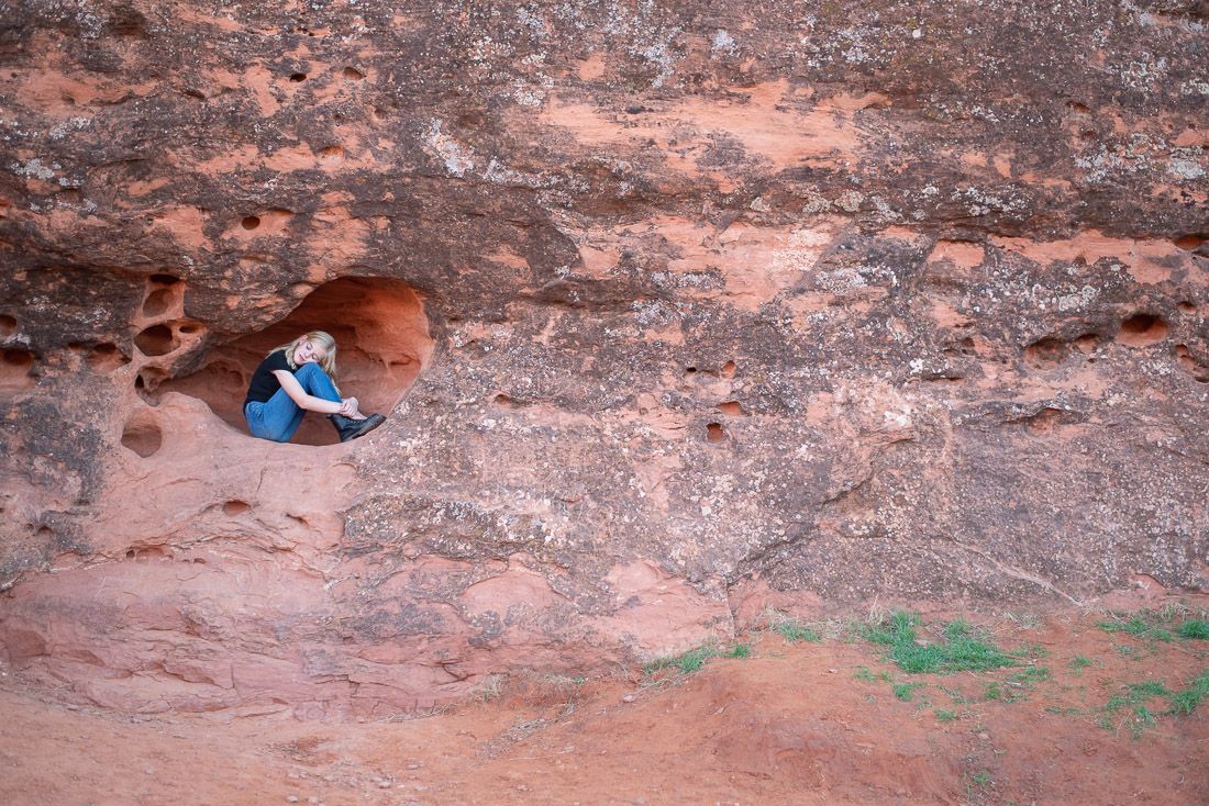 Girl nestled in a hole in the red rocks in St. George, Utah