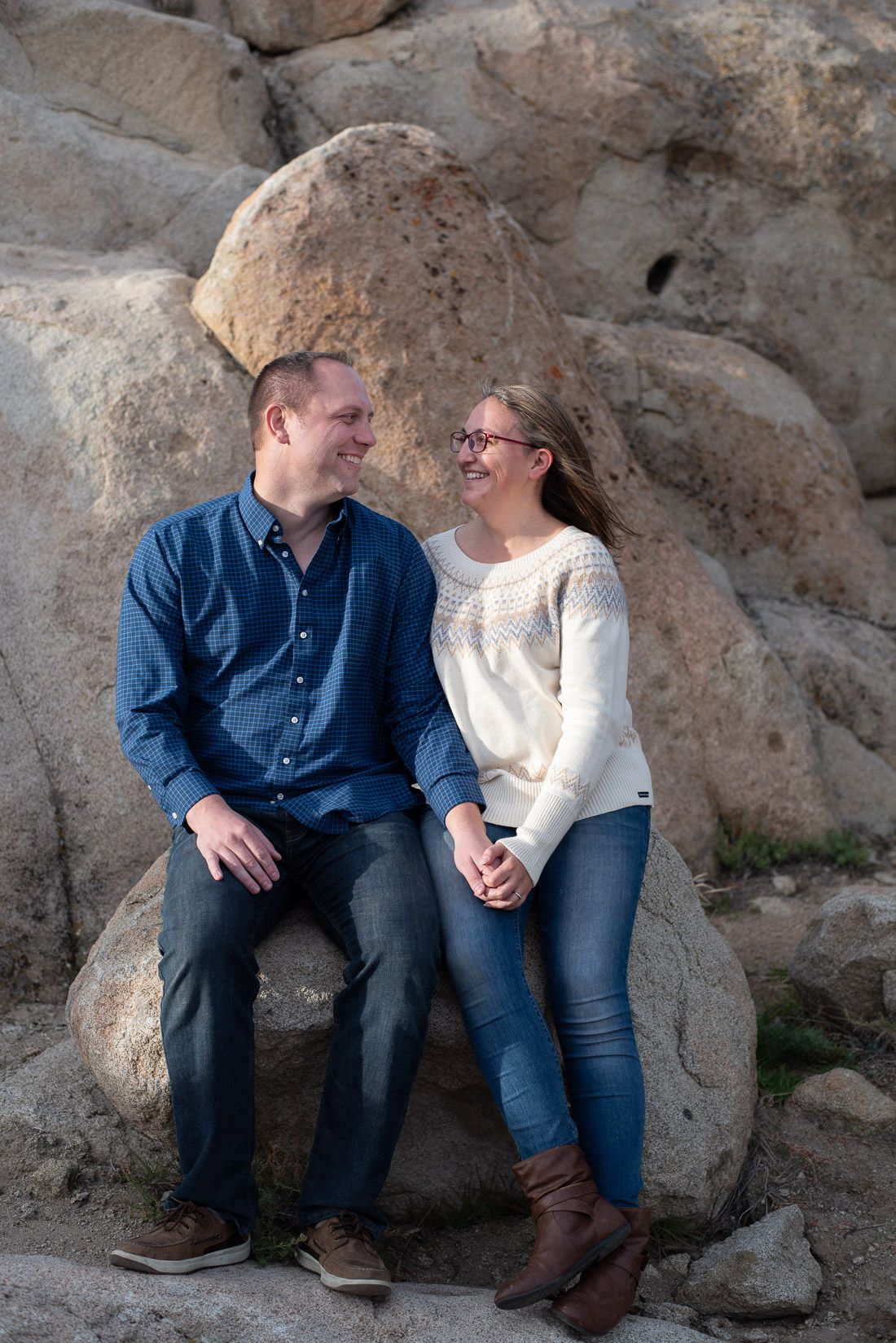 Mom and Dad sit on a rock holding hands and smiling at each other-Cedar City Utah Photographer- Bethany Allen