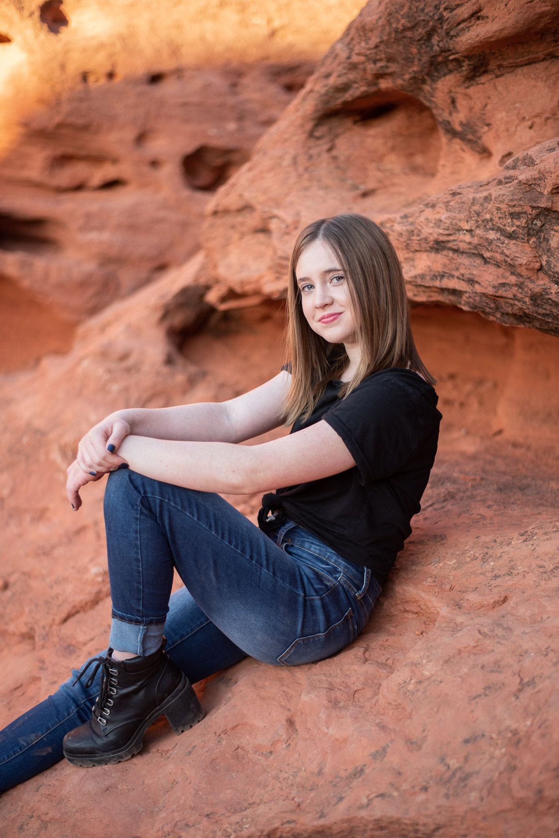 Side shot of teenager sitting on red rocks with her knee up-Utah Photographer