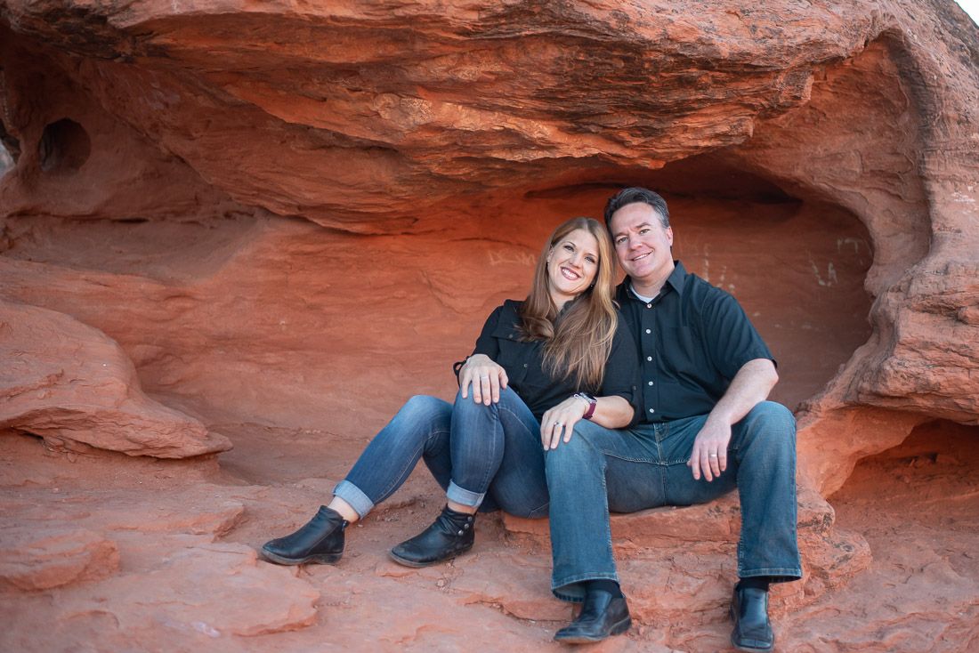 Wife leans back against husband while sitting on red rock