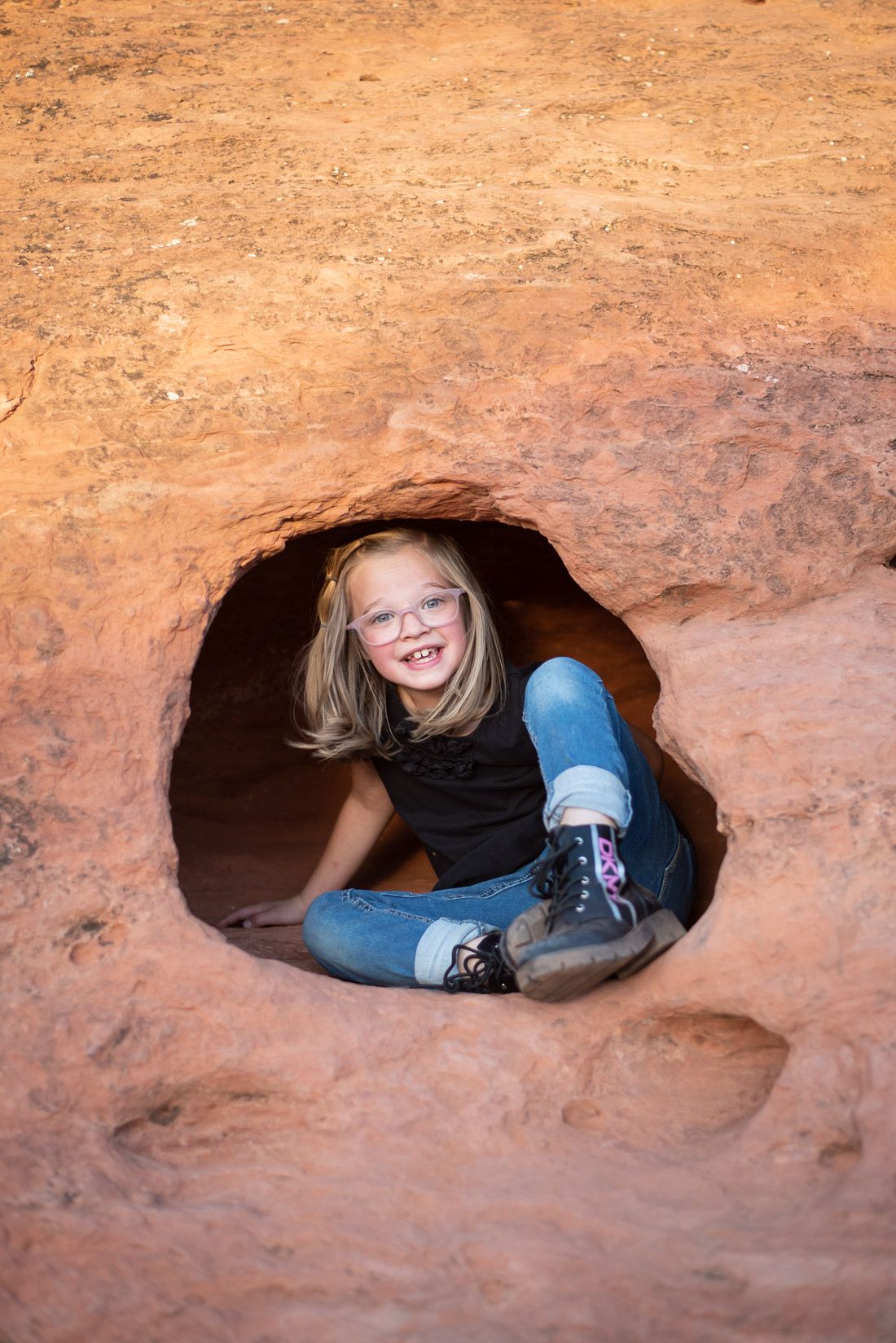 Young girl playing inside a hole in the red rocks